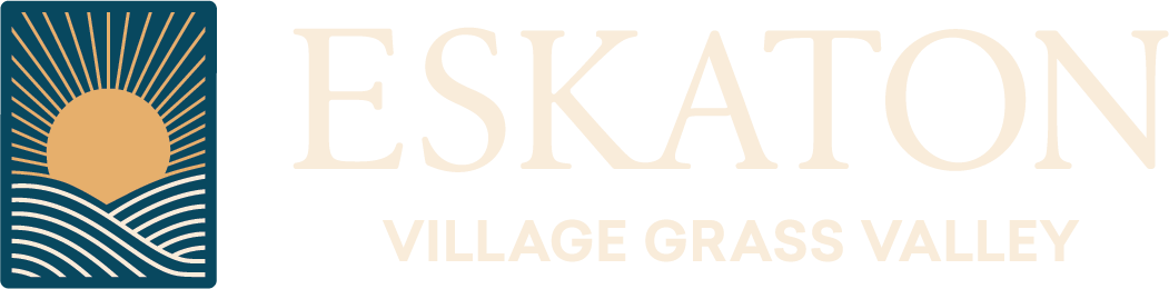 Logo for Eskaton Village Grass Valley. On the left, a sun rises over hills and waves in a blue and gold square. To the right, ESKATON is written in large, light gold letters with VILLAGE GRASS VALLEY below.
