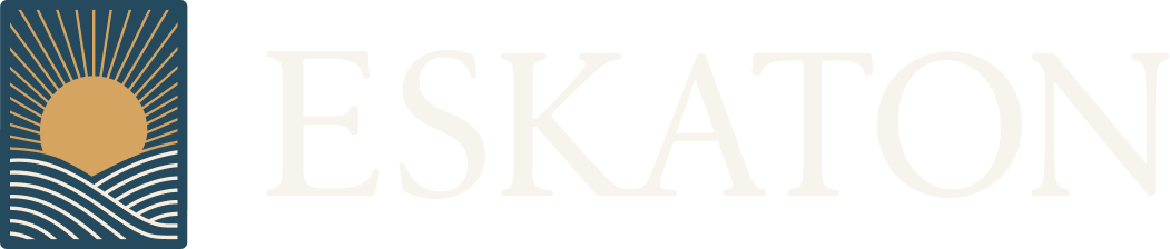 Logo with a golden sun rising over stylized white waves on a dark blue background, next to the faded word ESKATON in large, light-colored letters.